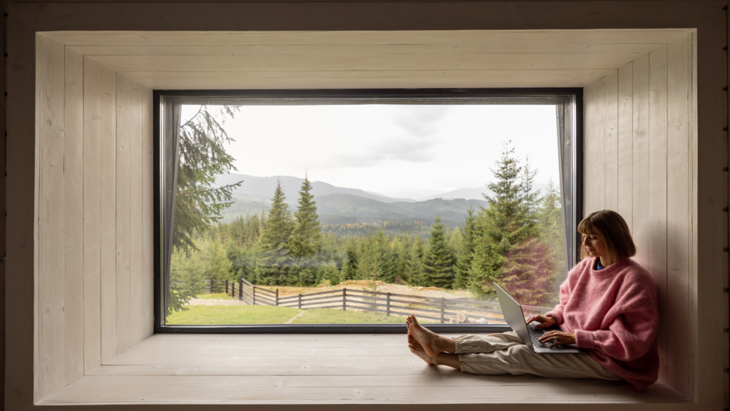 A focused woman sitting, reviewing data on her laptop and taking notes, symbolizing continuous monitoring and optimization of booking and service processes to enhance client experience and loyalty.